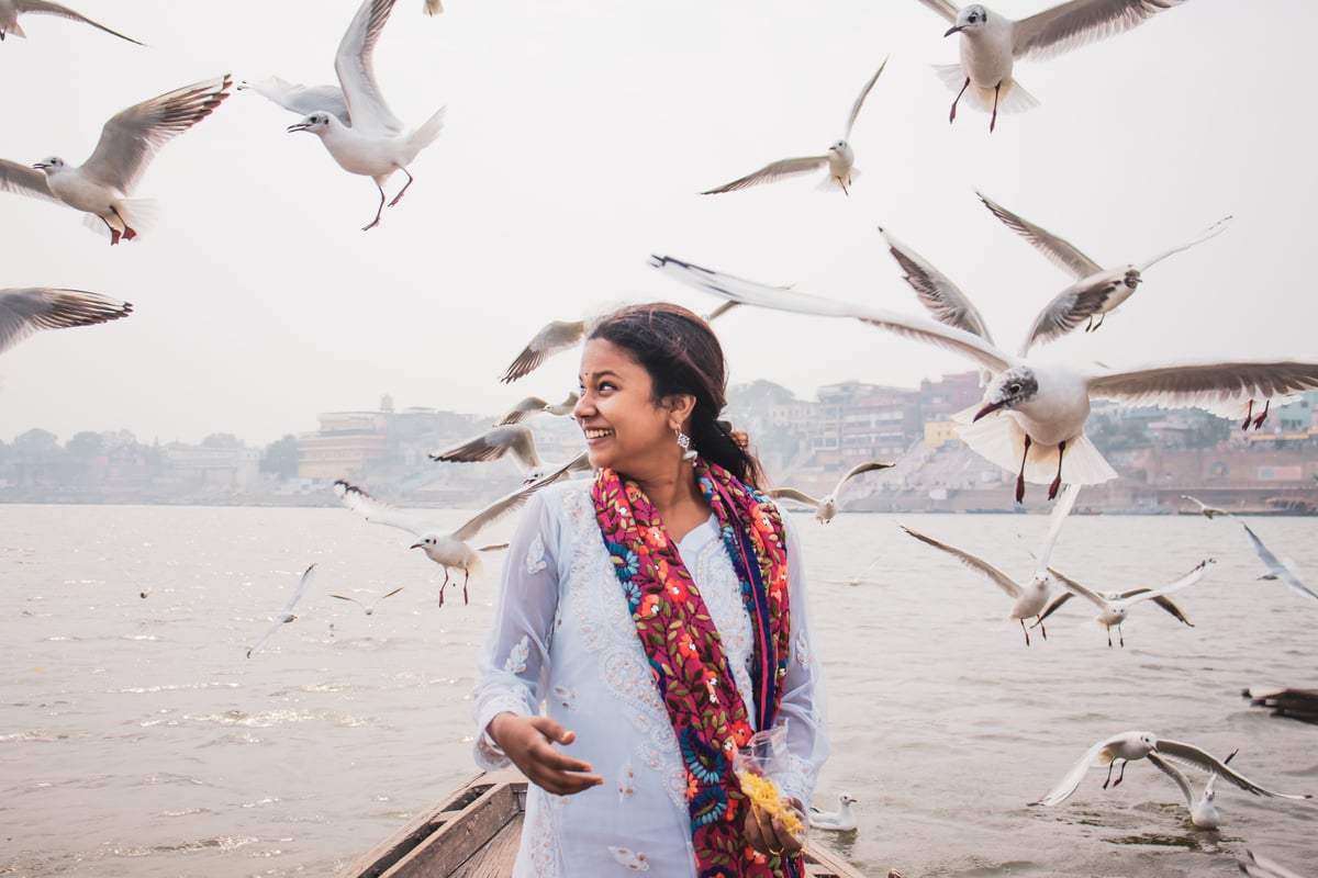 Happy Indian woman on boat against seagulls