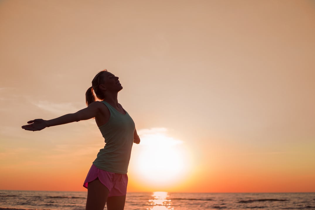 Happy and healthy woman standing in sunset